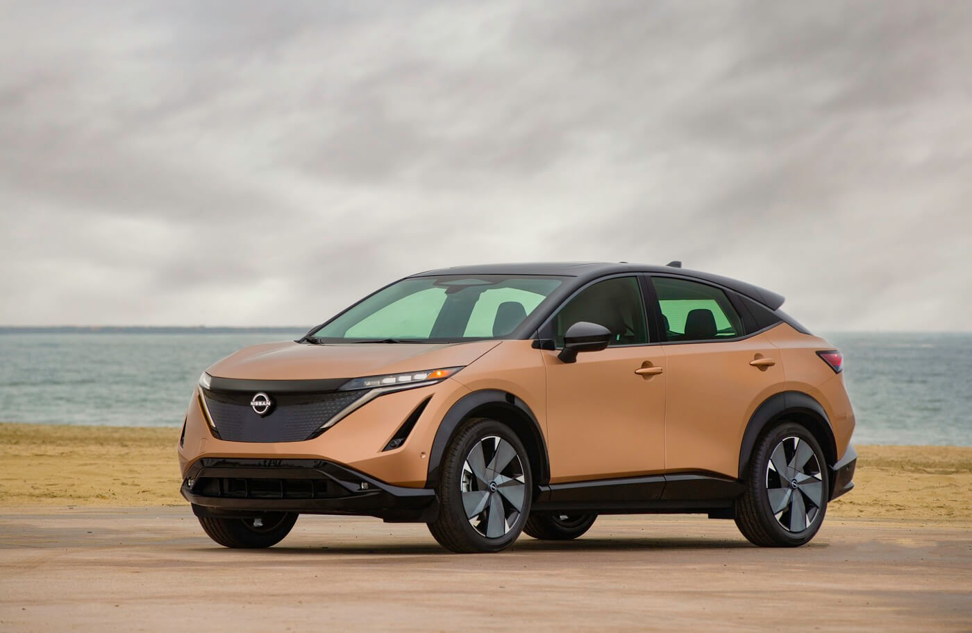 vue 3/4 avant d'un VUS électrique Nissan Ariya garé au bord d'une mer
