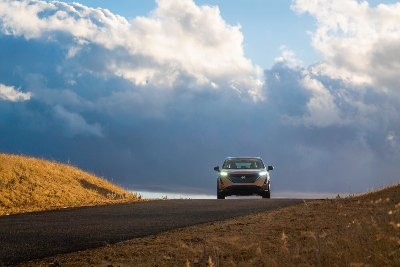 grande vue du ciel nuageux incluant le Nissan Ariya sur la route à l'aventure