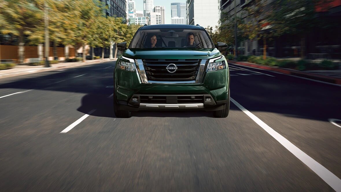 vue avant d'un Nissan Pathfinder 2022 couleur Vert nacré obsidienne roulant sur une route en ville